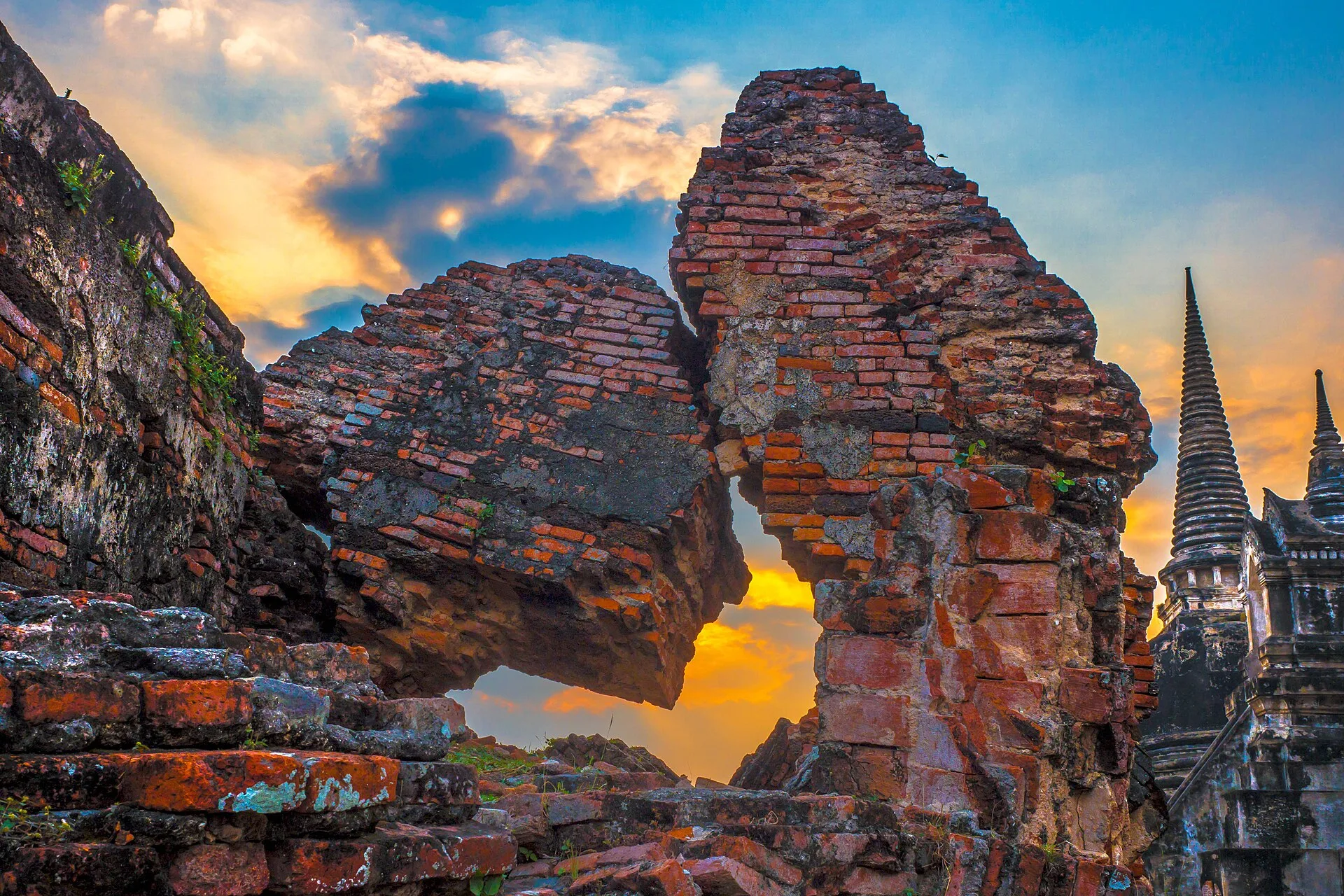 Bell-shaped chedis of Wat Phra Si Sanphet glowing through ruined brick at sunset in Ayutthaya