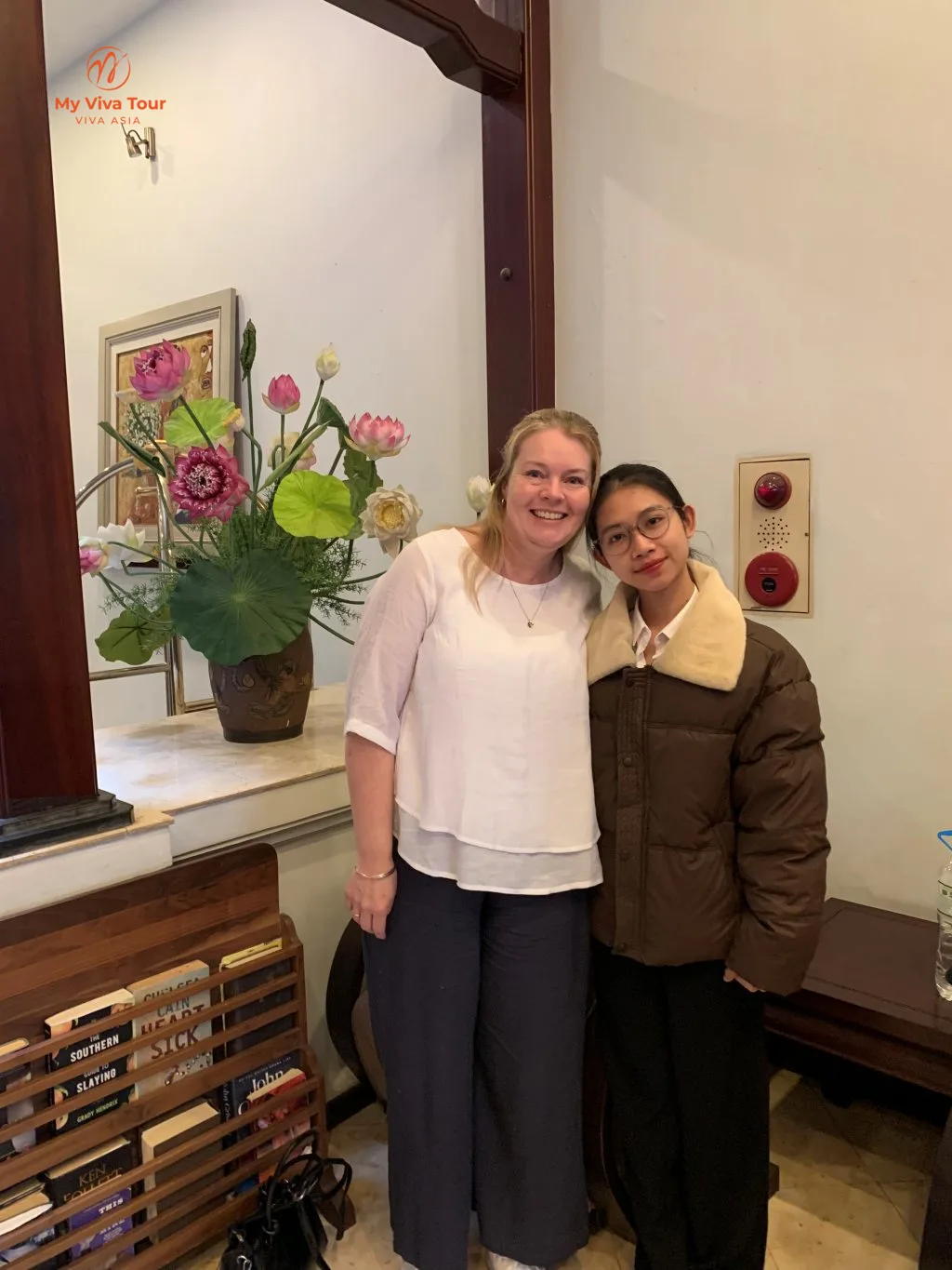 Caitlyn’s mother with her My Viva Tour planner beside a lotus display in a Hanoi hotel lobby, Vietnam