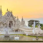 Chiang Rai travel guide — the all-white Wat Rong Khun (White Temple) glowing at sunset