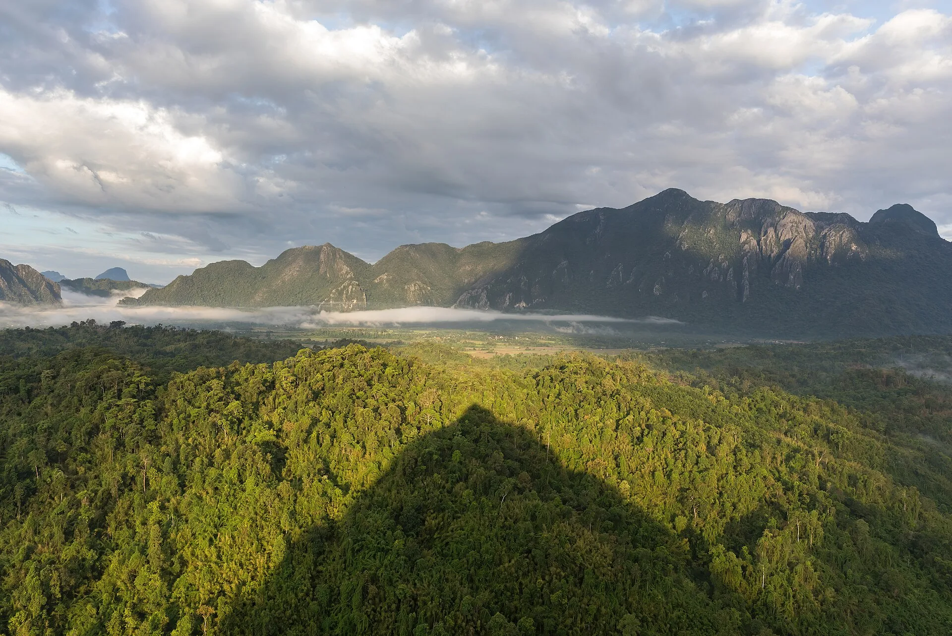 Misty green Vang Vieng valley and forested karst ridges seen at dawn from the Mount Nam Xay viewpoint