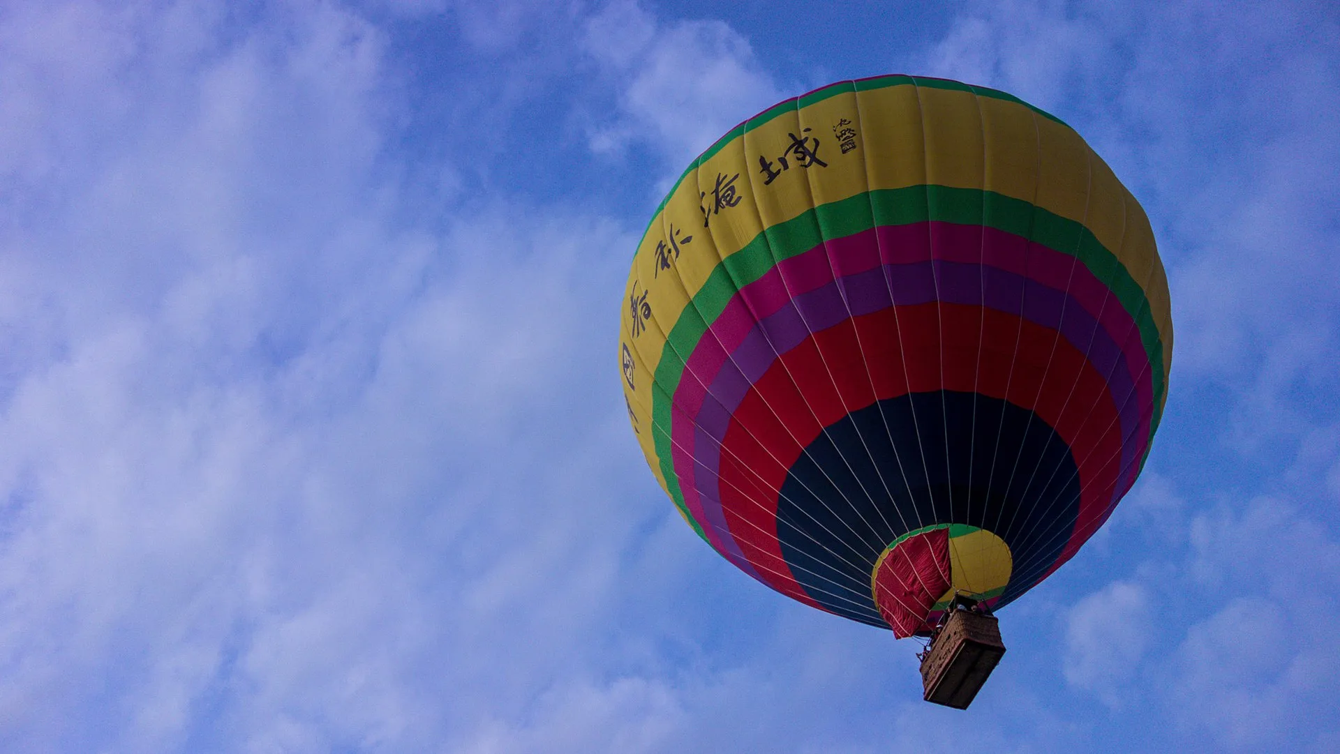 Colourful hot-air balloon drifting over Vang Vieng against a blue sky