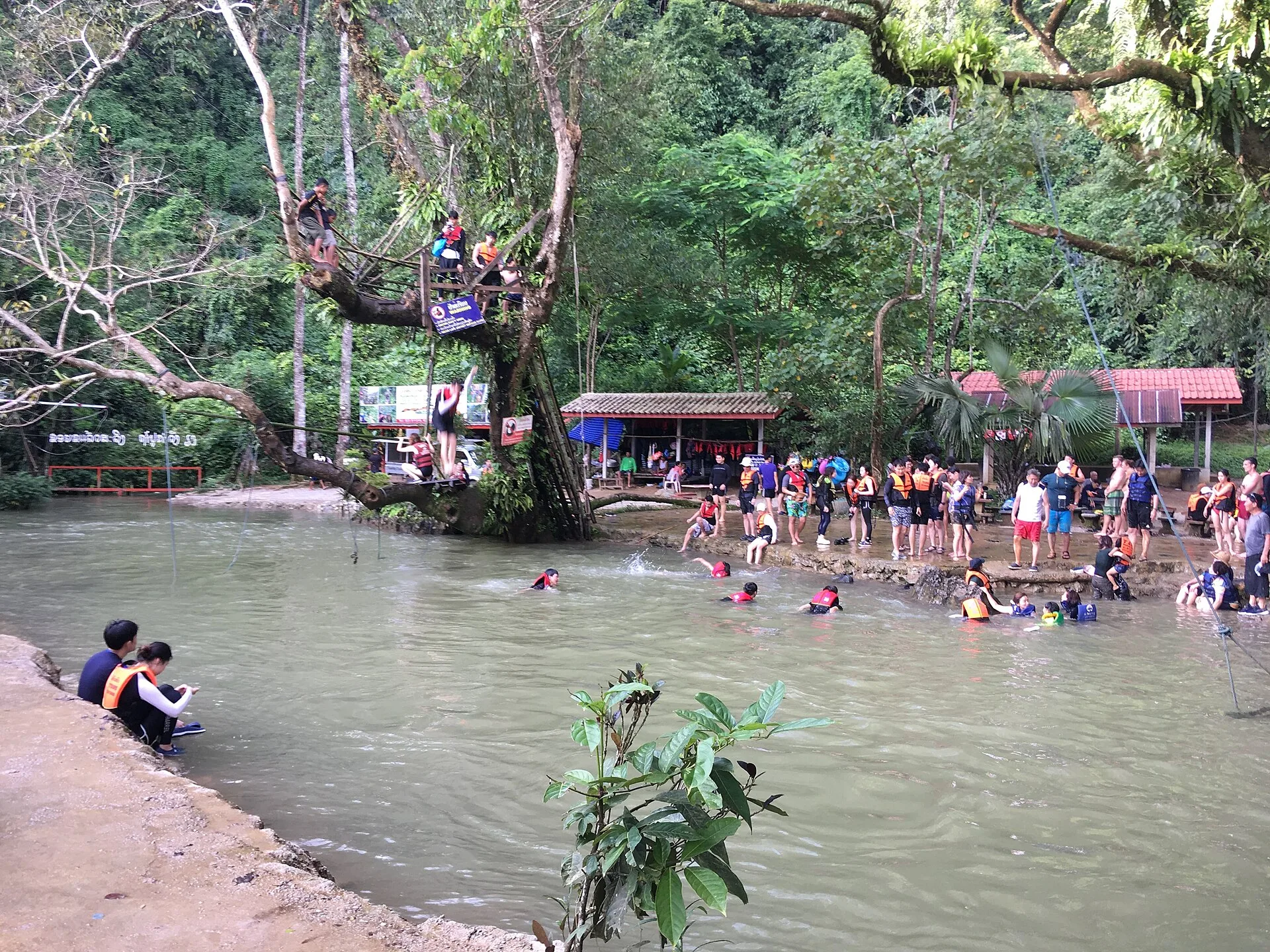 Travellers in life jackets swimming at the Blue Lagoon near Vang Vieng, surrounded by jungle