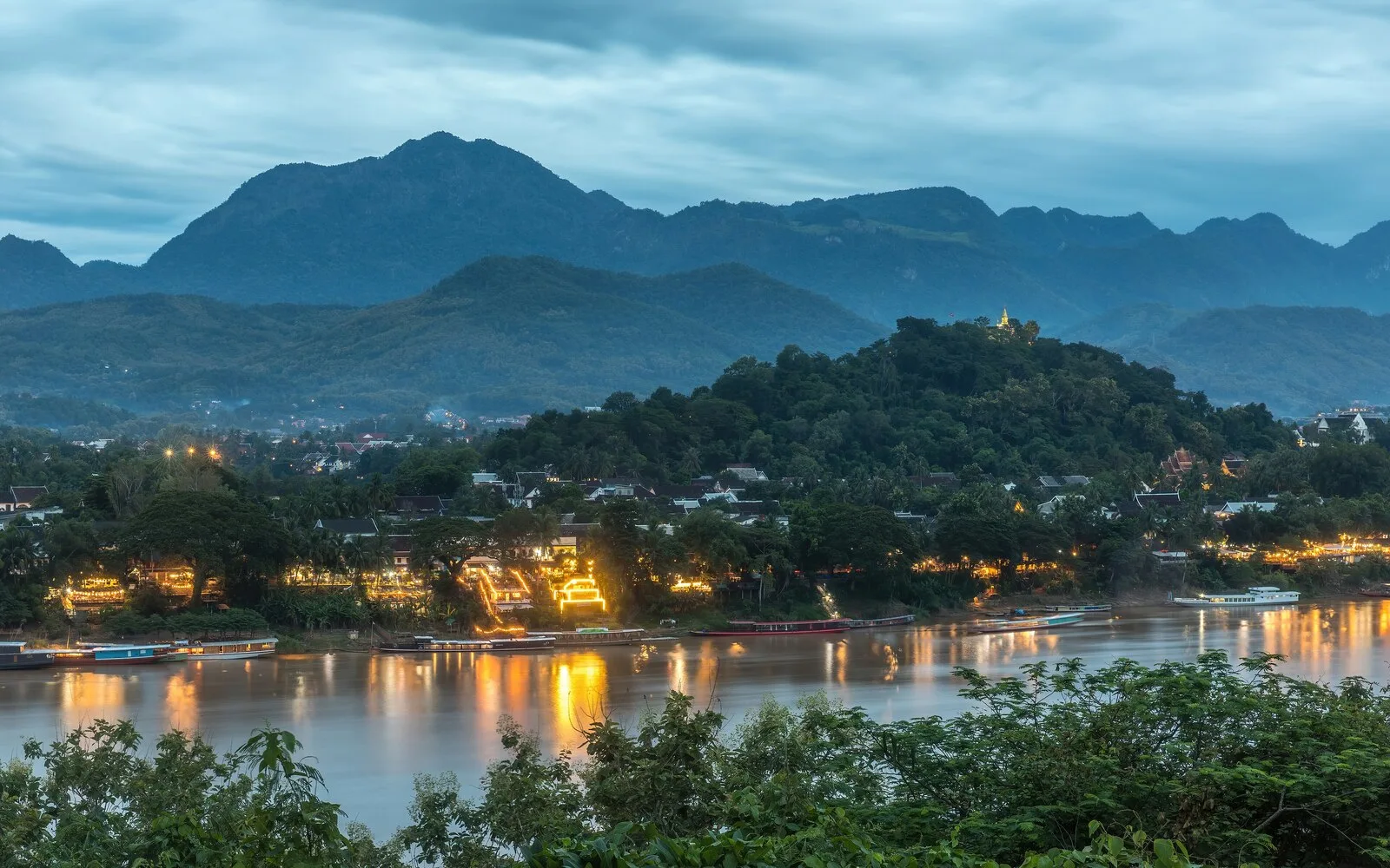 Mount Phou Si and the Mekong River at dusk with town lights in Luang Prabang