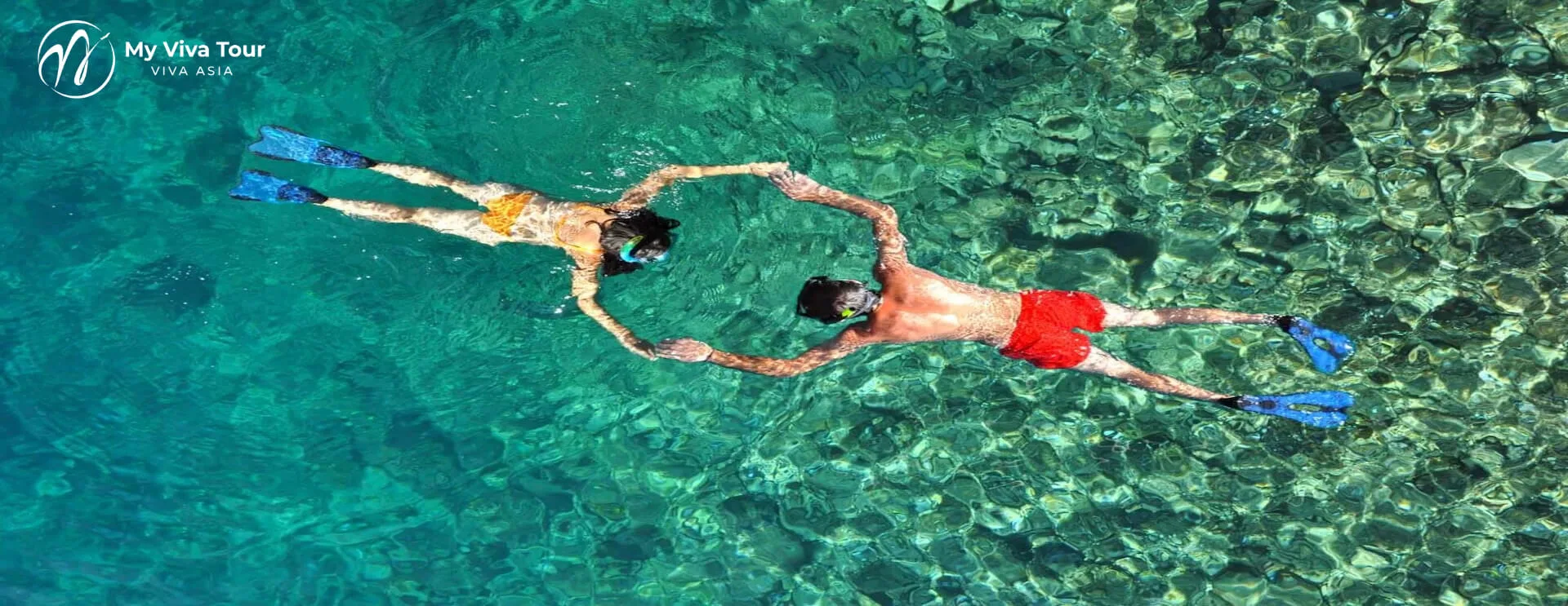 Couple snorkelling with fins in the clear turquoise water off Phuket, Thailand, seen from above