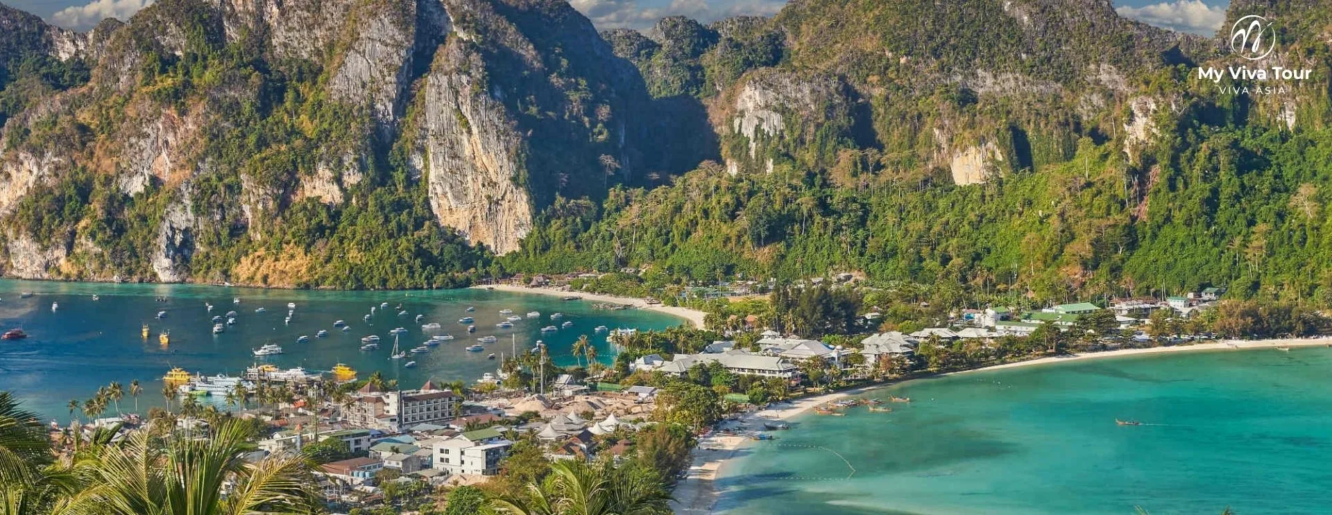 Aerial view of Phi Phi Don's twin bays, village and longtail boats framed by limestone cliffs near Phuket, Thailand