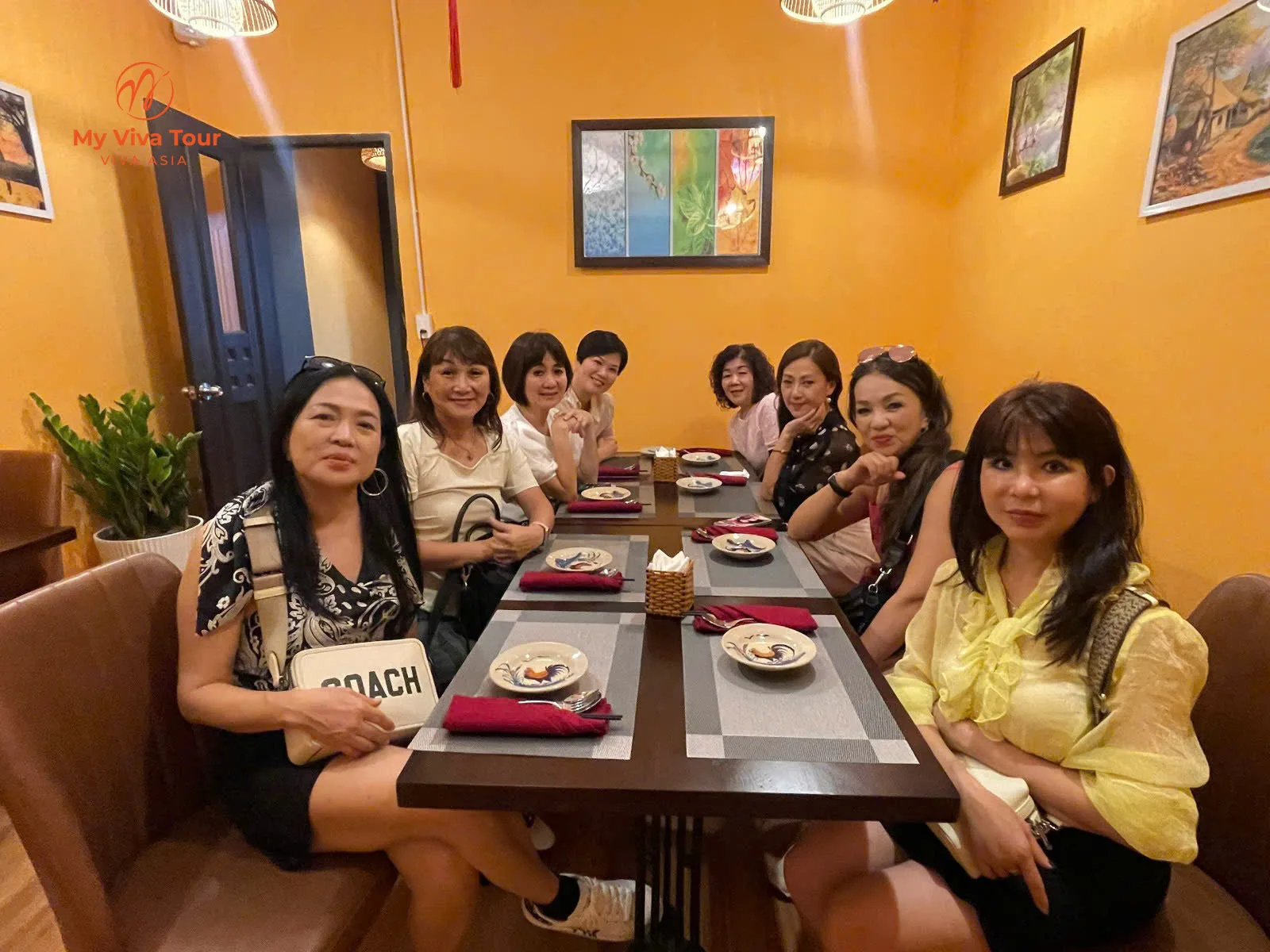 Jun Ong's group of eight women smiling together at a restaurant dinner table