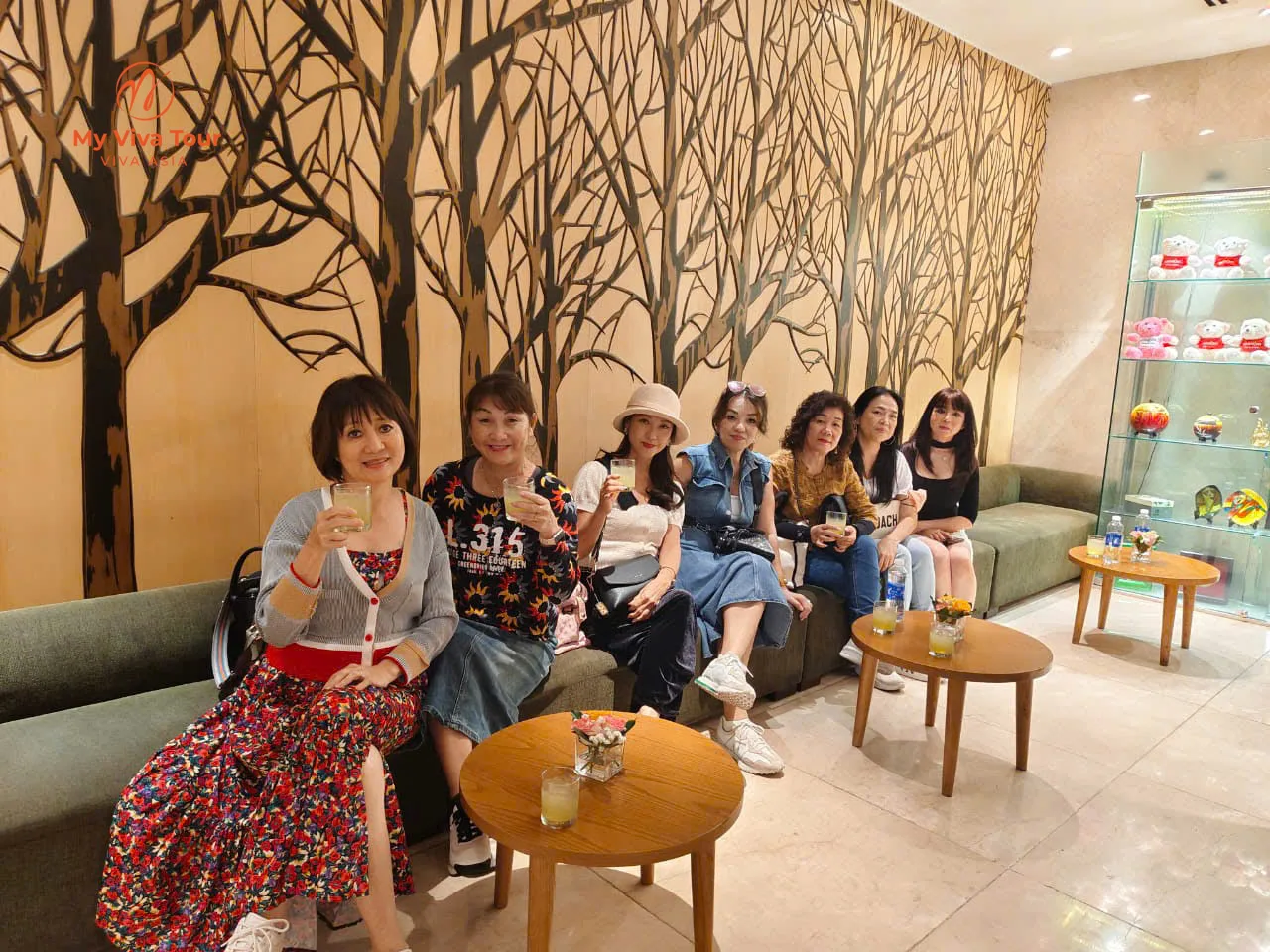 Friends relaxing with drinks on green sofas in a Da Nang hotel lobby lounge