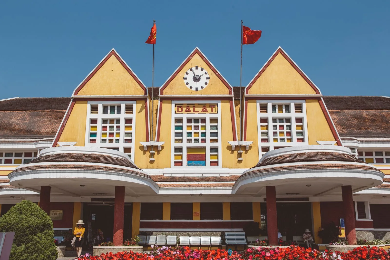 Colourful art-deco facade of the historic Da Lat railway station with flower beds in front