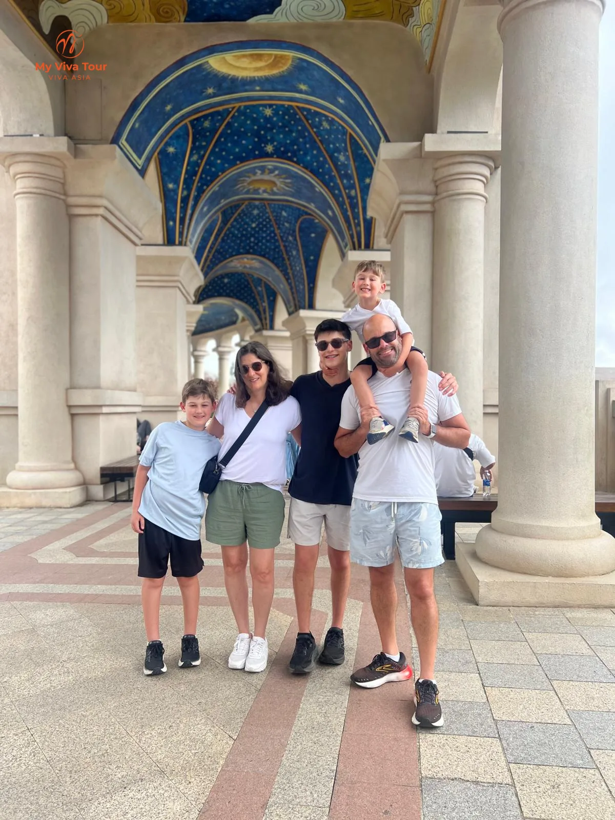 Family group photo under the painted ceiling of Ba Na Hills' French Village, Da Nang