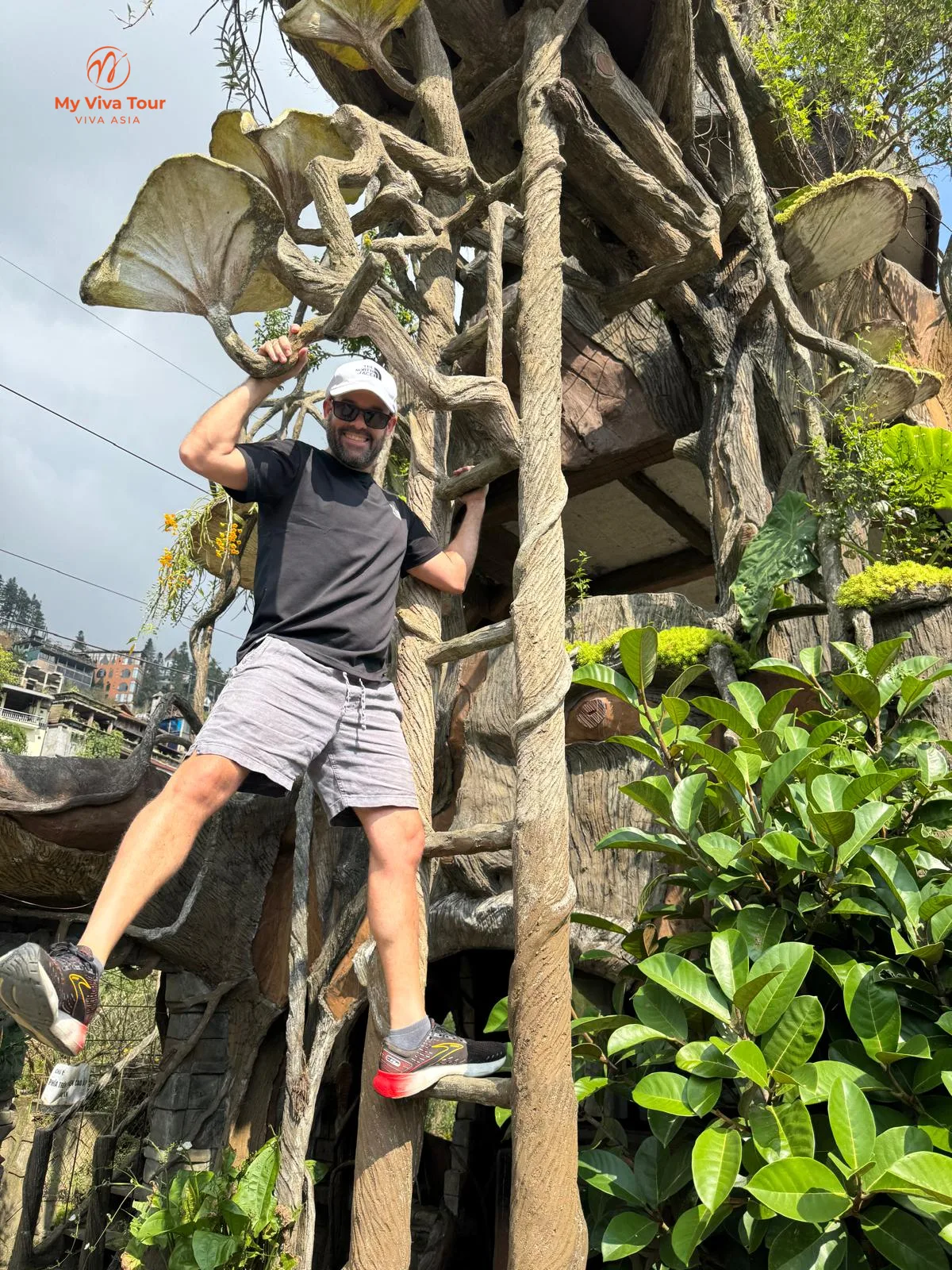 Dad climbing a giant carved-tree sculpture at a photo garden in Sapa, Vietnam