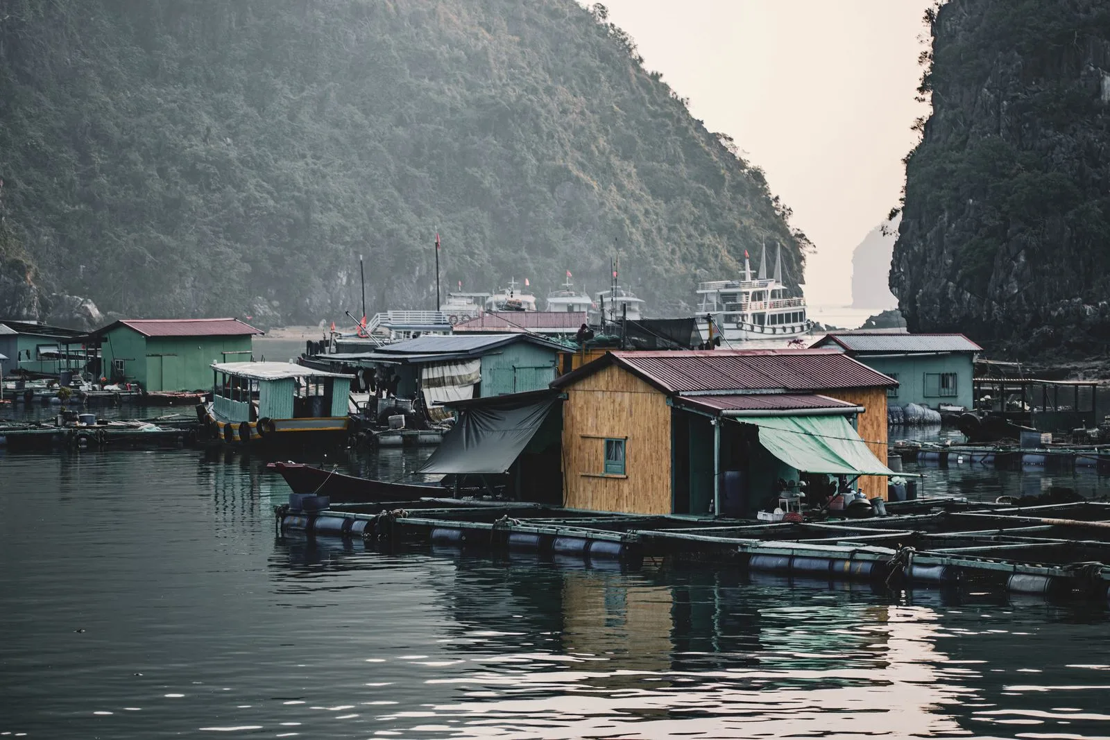 Floating fishing village houses on Ha Long Bay surrounded by limestone cliffs