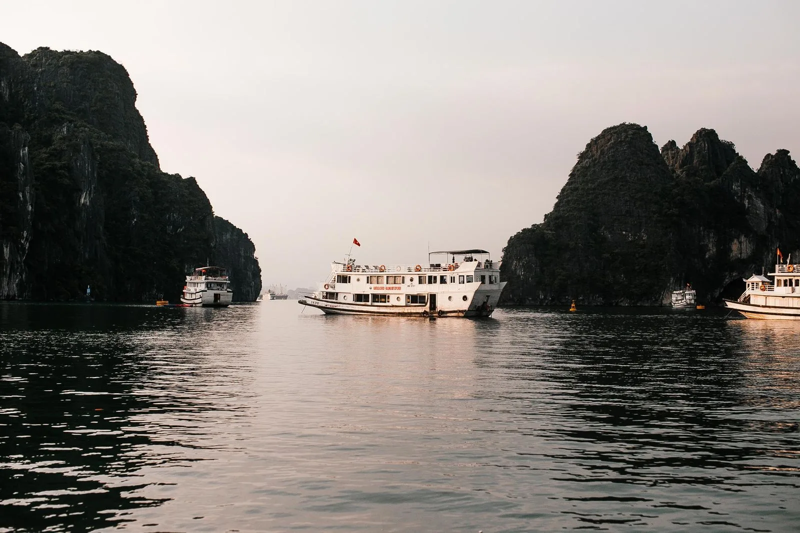 Overnight cruise boats anchored among Ha Long Bay's karst islands at dusk