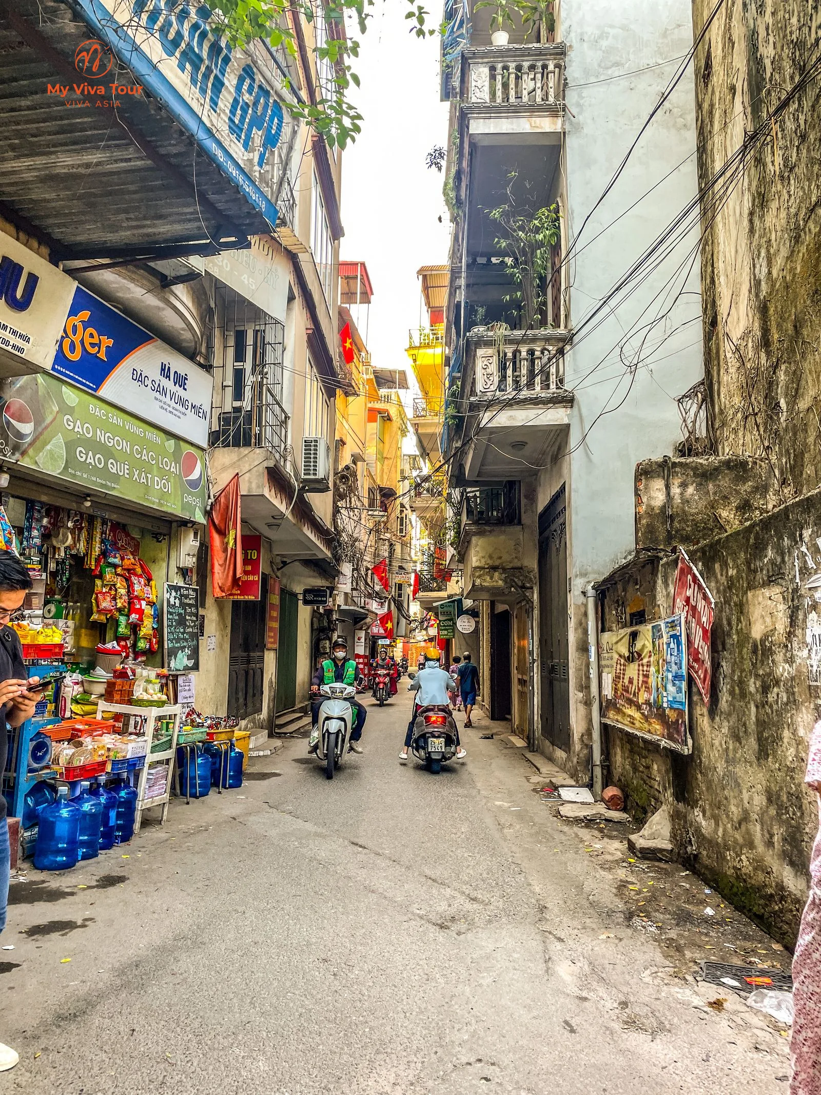 Motorbikes and shopfronts on a narrow Hanoi Old Quarter street