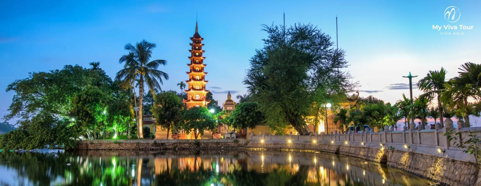 Tran Quoc Pagoda tower lit up at dusk and reflected in West Lake in Hanoi, Vietnam