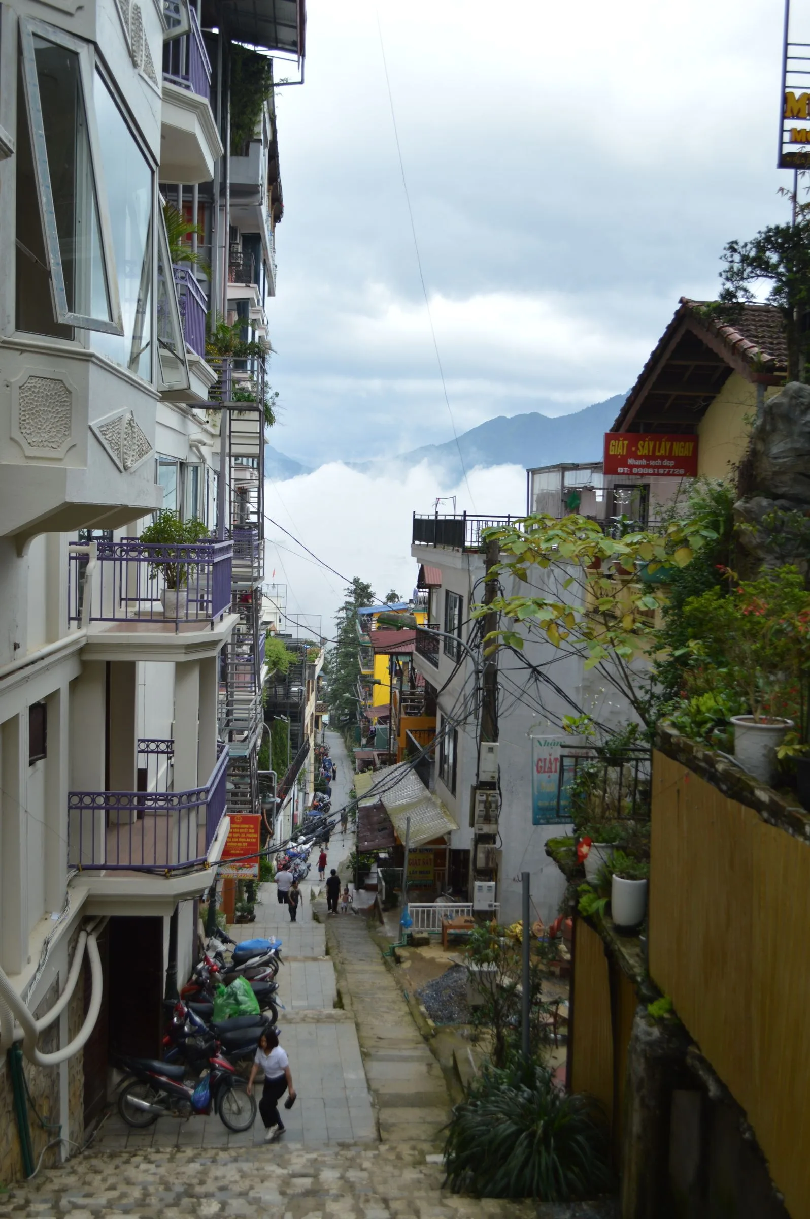 Steep hillside street in Sa Pa town with mist filling the valley below