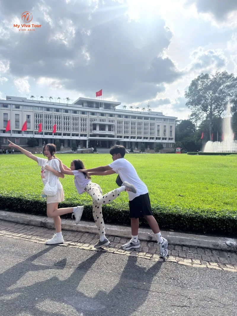 Jerome's teens fooling around on a lawn in front of a landmark building in Ho Chi Minh City