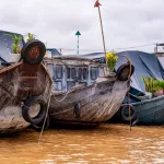 Traditional wooden cargo boats moored on the brown Mekong River, a classic scene for a Mekong Delta travel guide