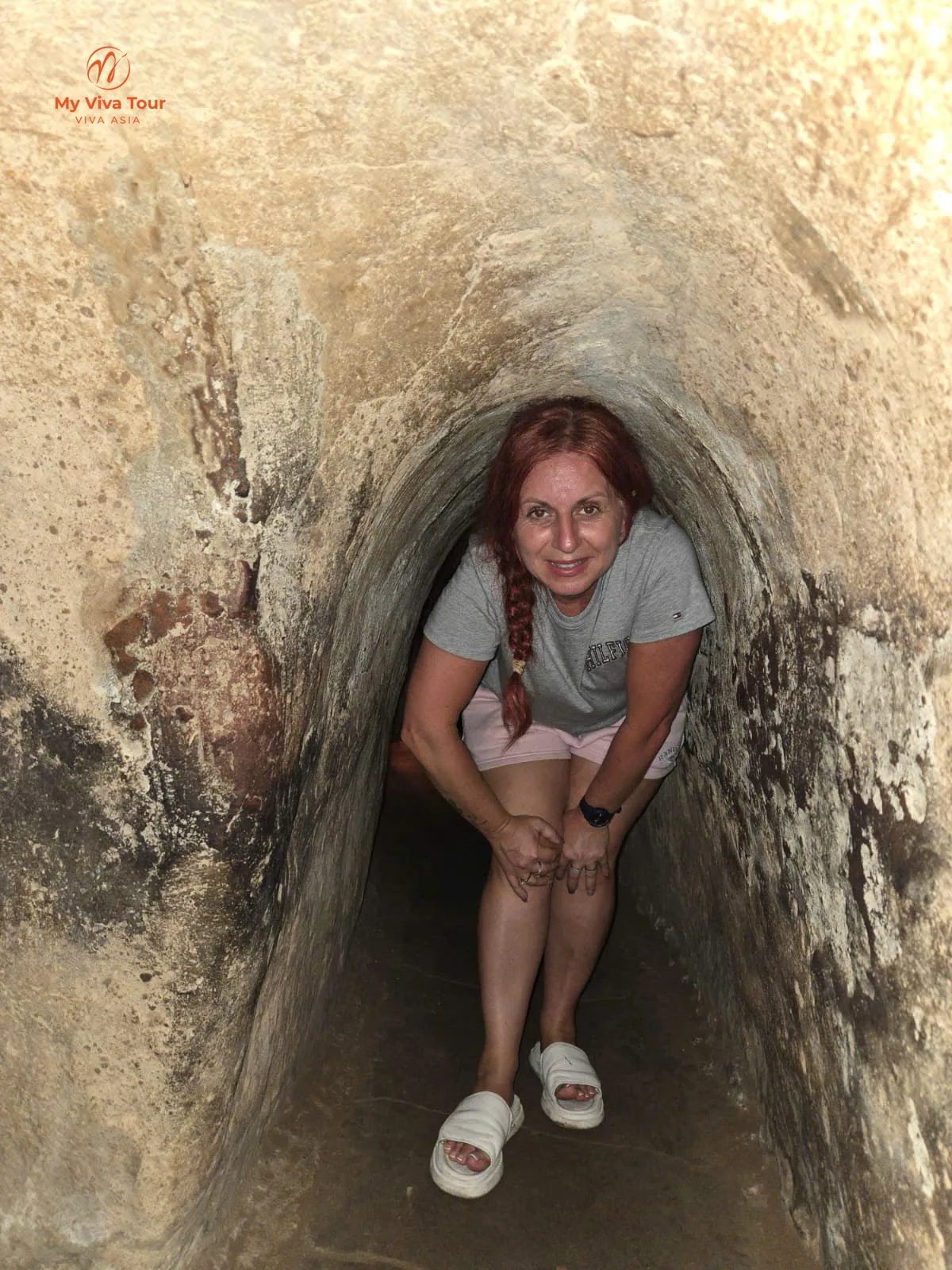 Traveller climbing through the narrow stone tunnel at Ninh Binh's Mua Cave