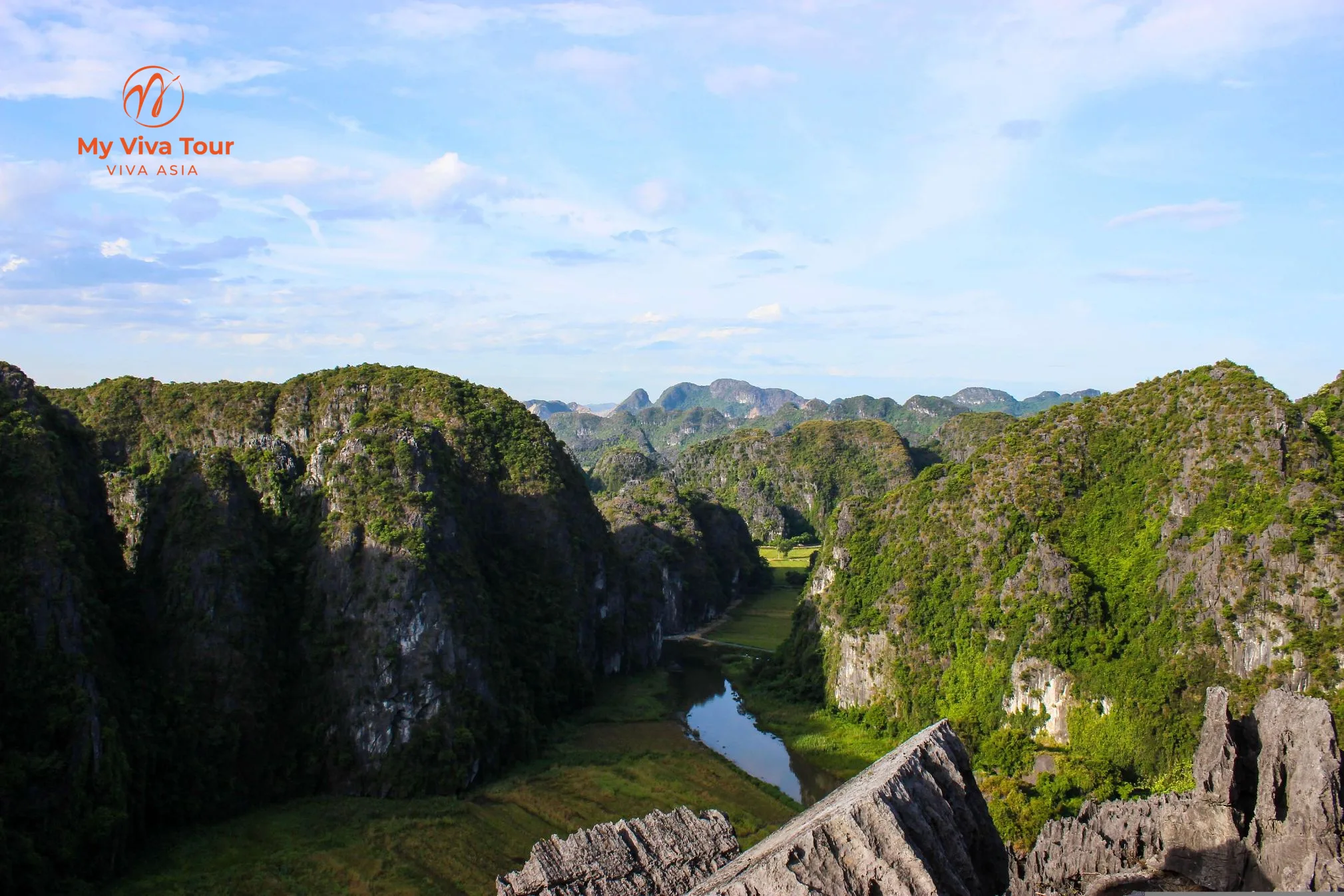 Panoramic view from Hang Mua over limestone karst mountains and the winding Ngo Dong River through rice fields in Ninh Binh
