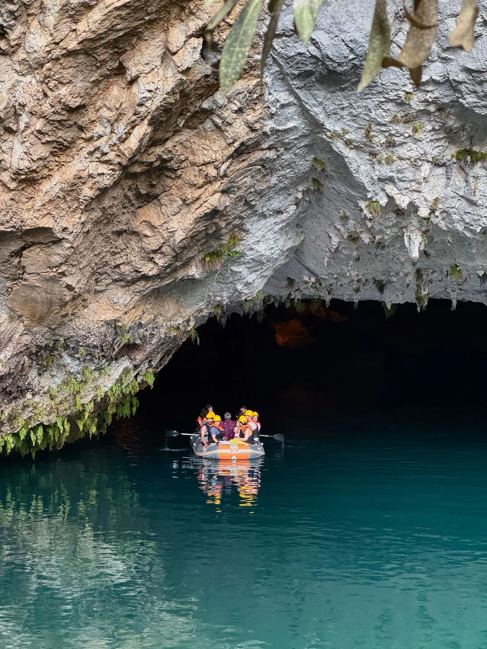 Helmeted visitors on an inflatable raft entering a river cave in Phong Nha-Ke Bang National Park