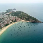 Quy Nhon travel guide: aerial view of the coastline, golden beach and fishing village with wooden boats