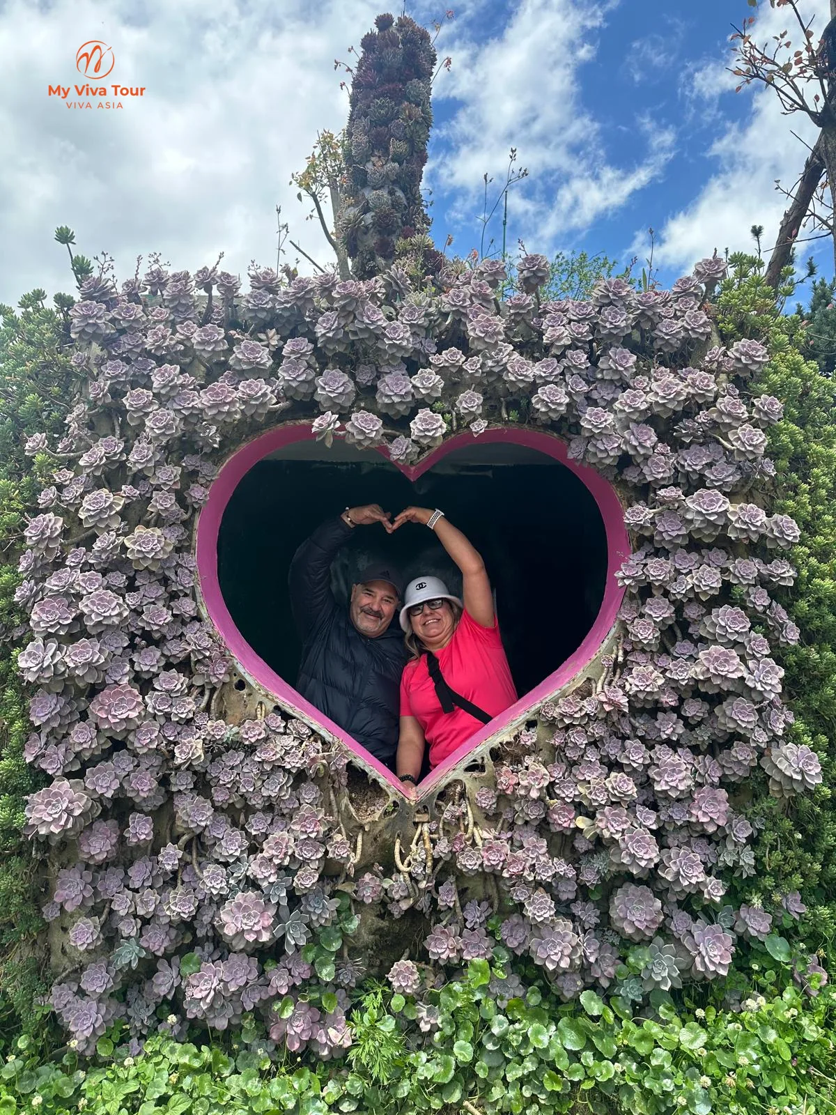 Couple forming a heart shape inside a flower-covered heart frame, Sapa