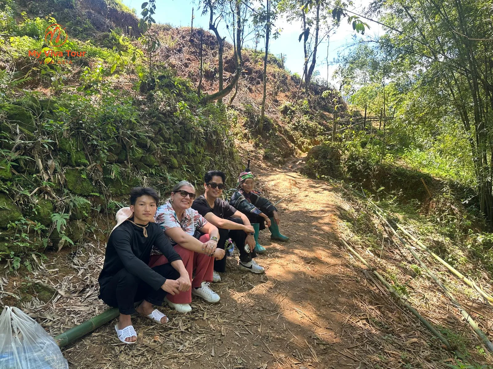 Trekkers resting on a forest trail with local villagers in Sapa
