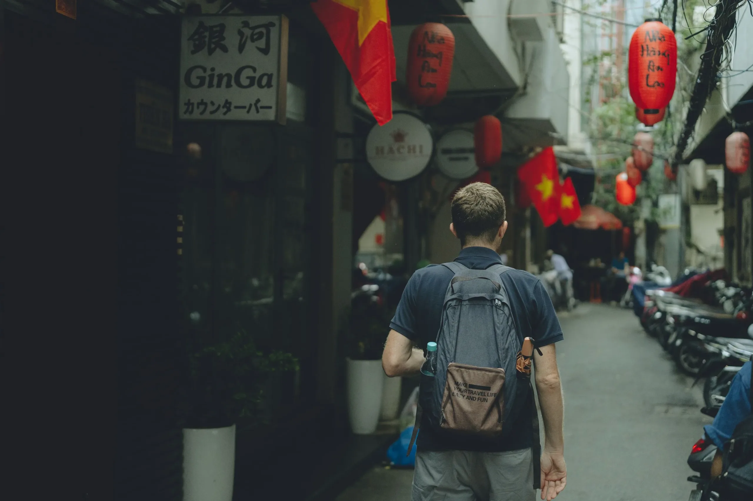 Solo traveller walking a lantern-lit Vietnamese street with a backpack