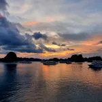 Teresa Bellis Vietnam anniversary trip — sunset over Ha Long Bay cruise boats and limestone karsts