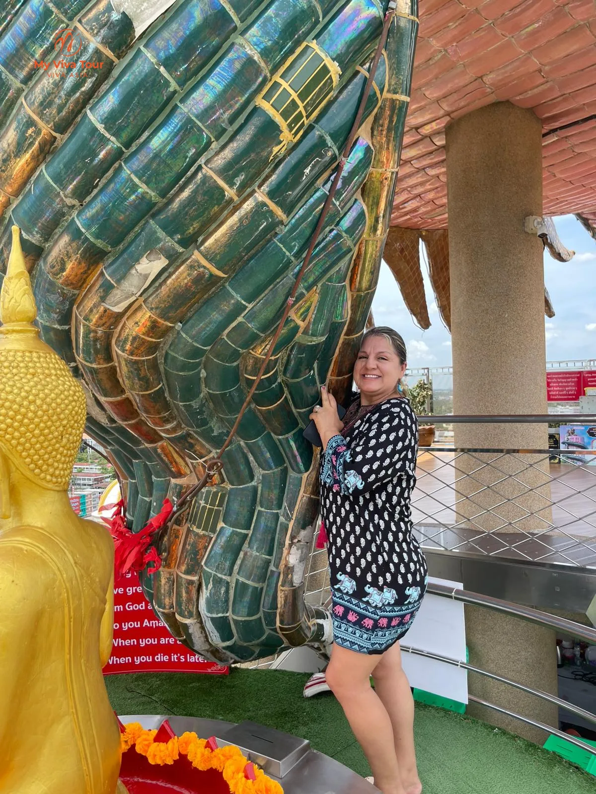 Traveller beside an ornate dragon-shaped temple structure in Thailand