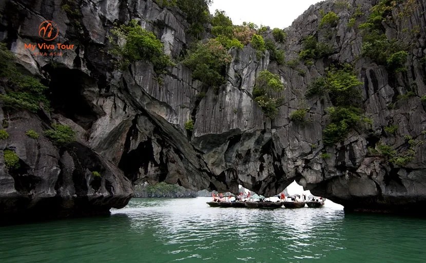 Traditional wooden boats passing towering limestone karsts in Ha Long Bay, Vietnam