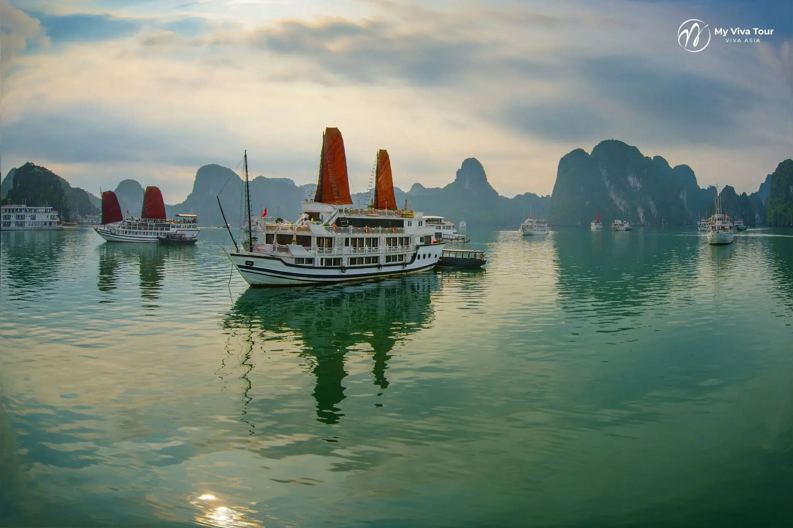 Traditional red-sailed cruise boat moored among the karsts of Ha Long Bay