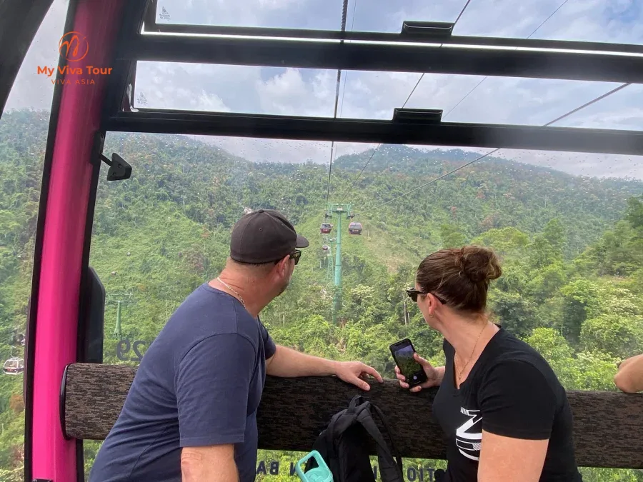Travellers riding the Ba Na Hills cable car above forested hills near Da Nang