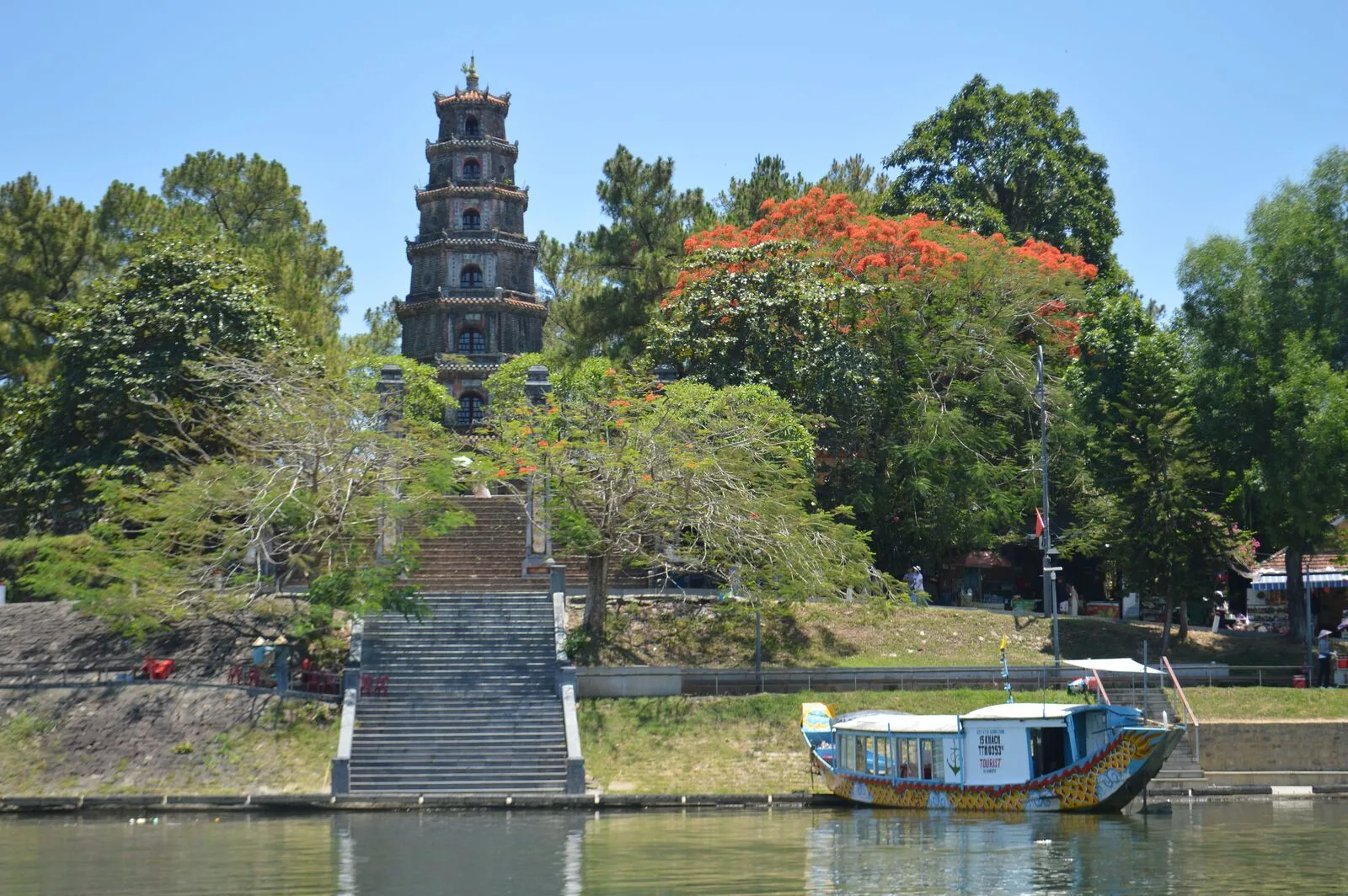 The seven-storey Phuoc Duyen Tower at Thien Mu Pagoda seen from the Perfume River, with a dragon boat moored at the steps