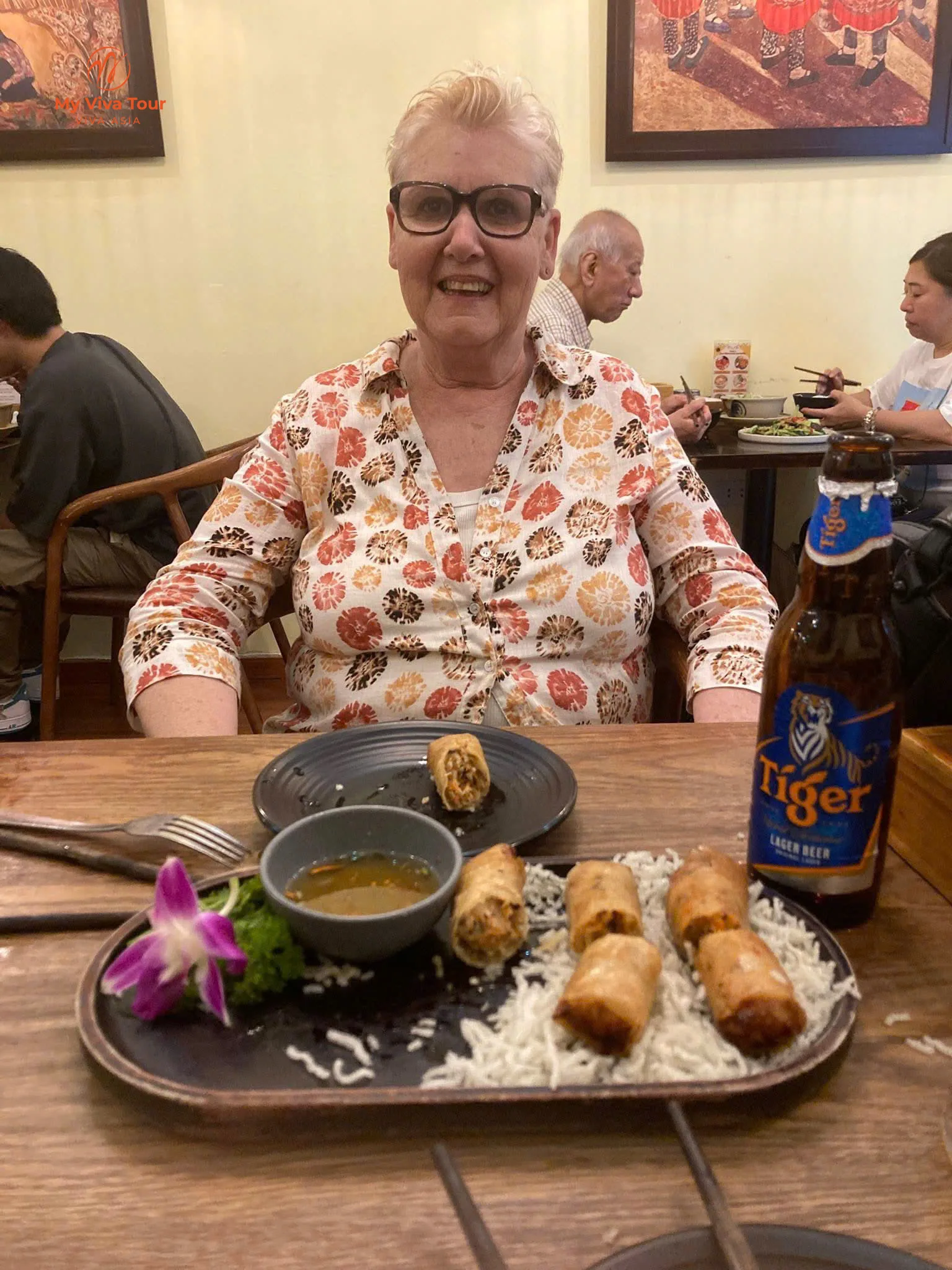A plate of crispy Vietnamese spring rolls with dipping sauce and a Tiger beer