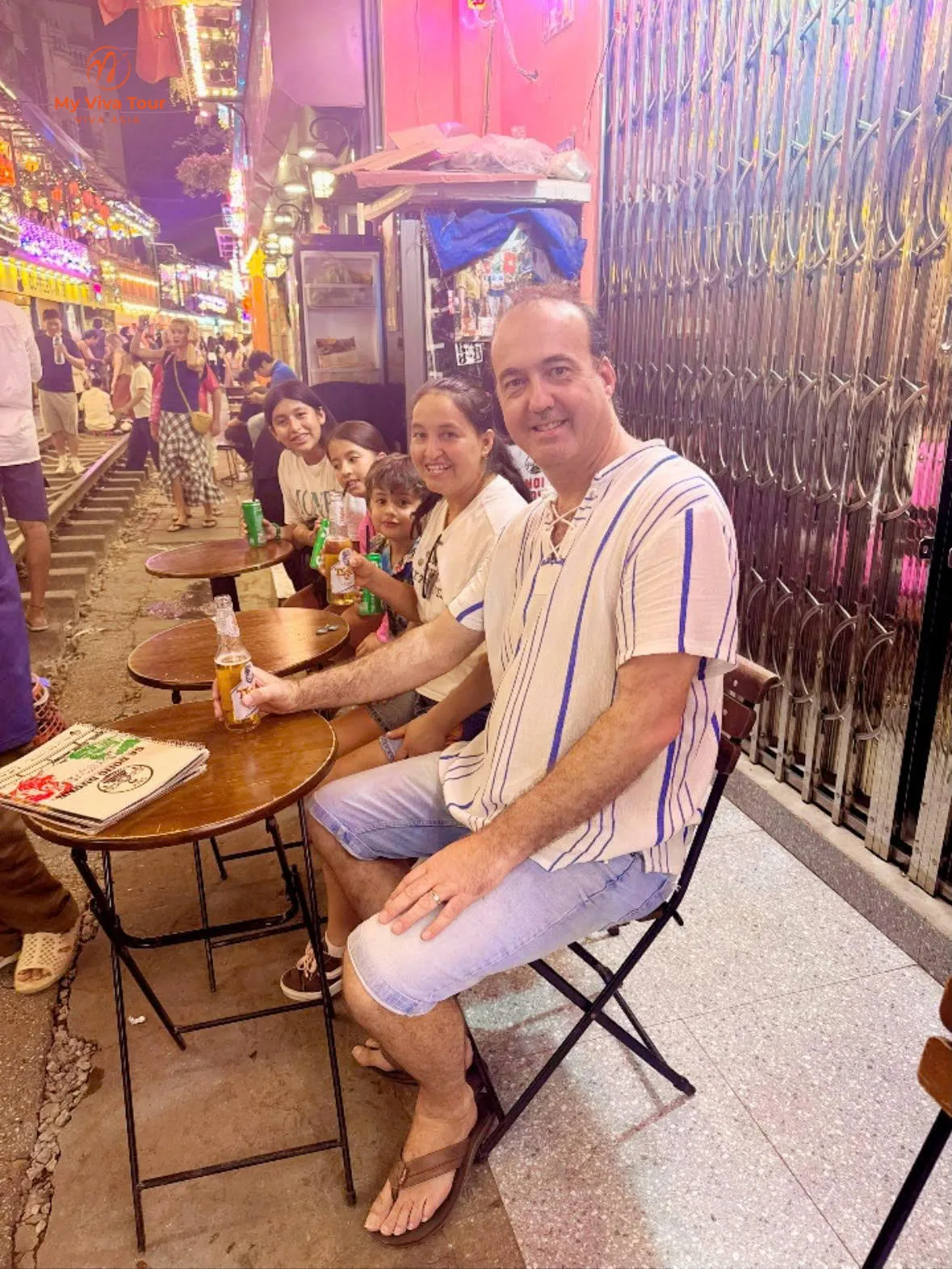 Family at a café beside the railway tracks on Hanoi's Train Street at night