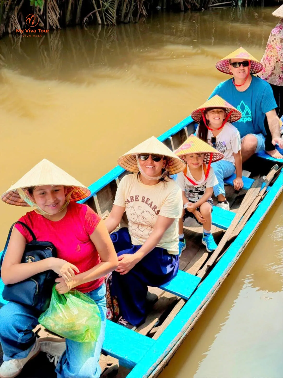 Family in conical hats on a wooden sampan on a Mekong Delta canal