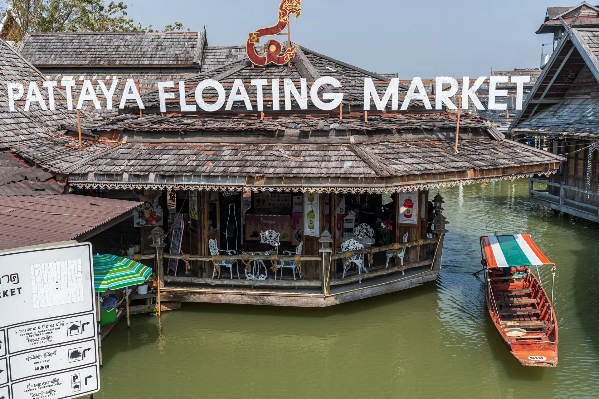 Wooden pavilion under the Pattaya Floating Market sign with a longtail boat on the canal