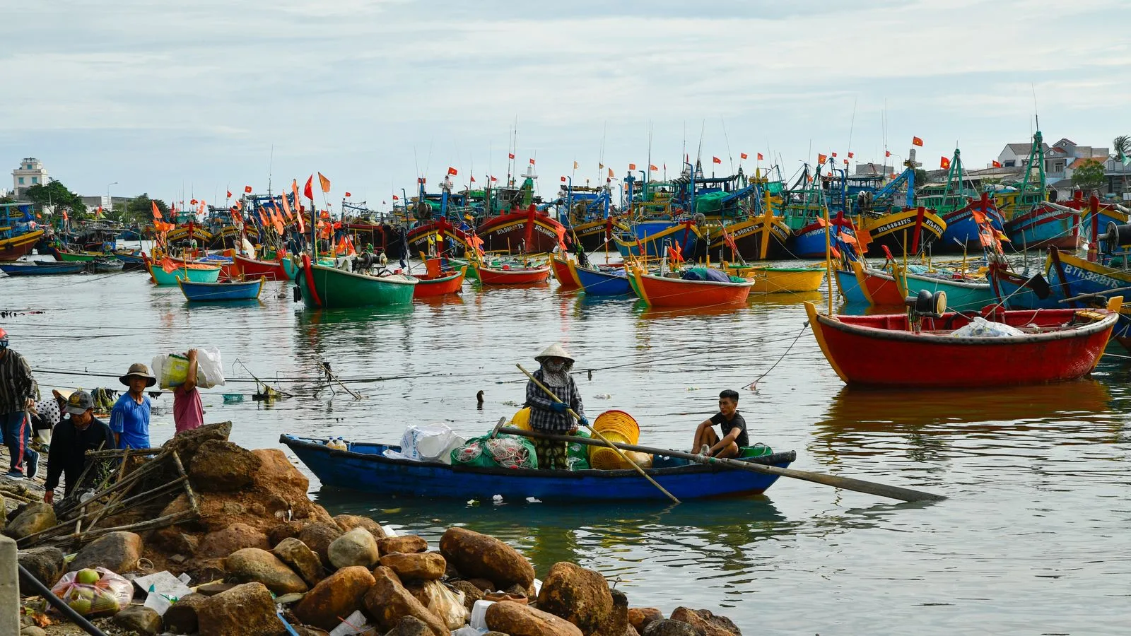 Colourful wooden fishing boats with red flags moored in Phan Thiet harbour