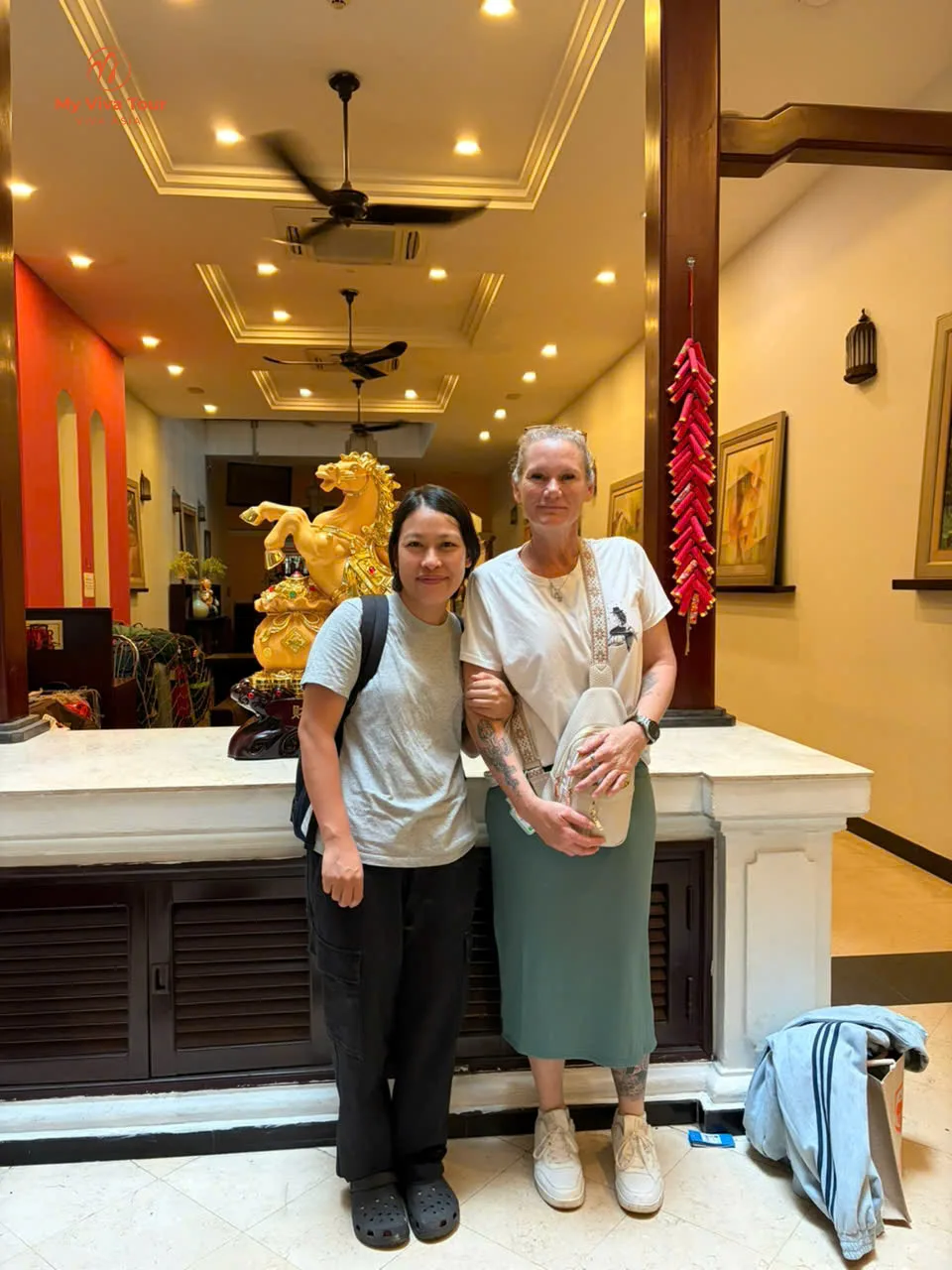 Demelza standing beside a gold horse statue and red firecracker strings in a Vietnam hotel lobby